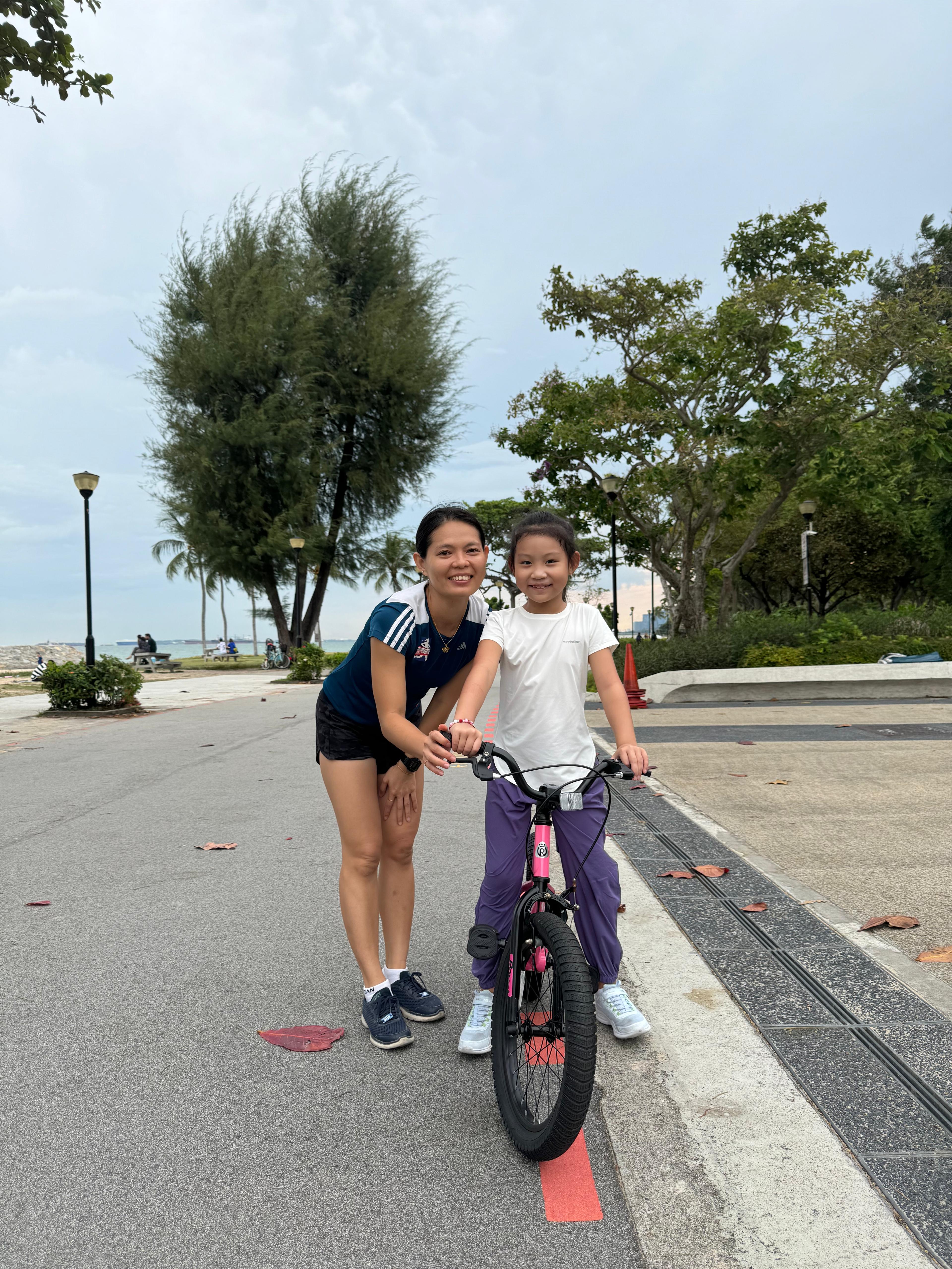 A child wearing sunglasses rides during a cycling lesson at a Tampines park